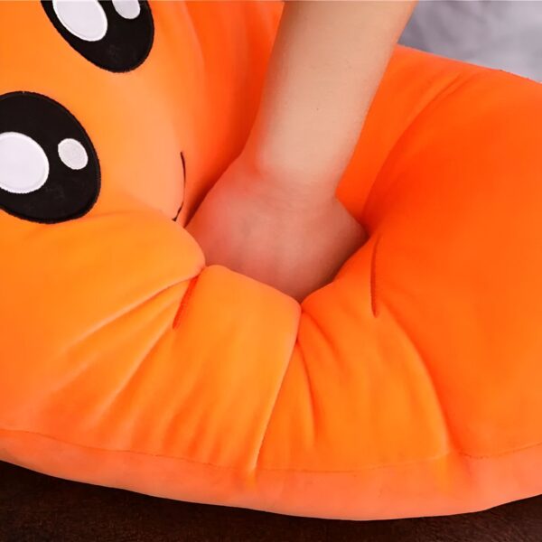 Un coussin en forme de visage souriant orange avec de grands yeux noirs et blancs.