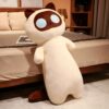 Une peluche en forme de chat blanc avec de grands yeux bleus et des oreilles brunes. Le chat est assis sur un lit.
