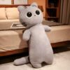 Grande peluche de chat gris posée sur un lit. Le chat a de grands yeux noirs et une expression amusante.