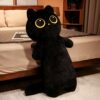 Un gros chat noir en peluche avec de grands yeux jaunes, debout sur un lit.