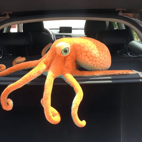peluche-geante-pieuvre-orange-jouet-doux-enfant-et-adulte-4a-2 Une grosse pieuvre en peluche orange avec des yeux bleus dans le coffre d'une voiture.