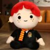Peluche de Ron Weasley, un personnage de la saga Harry Potter, portant l'uniforme de Gryffondor. Il est assis sur un sol en bois.