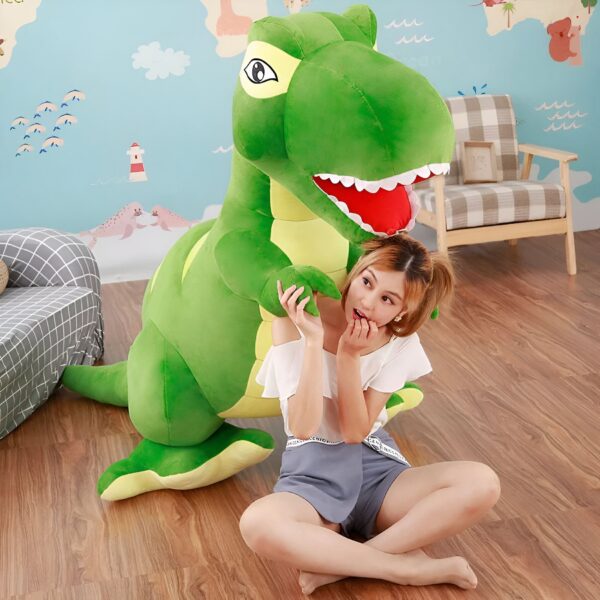 Une jeune femme assise sur un plancher en bois avec un grand dinosaure en peluche vert. Le dinosaure a de grandes dents et des yeux jaunes. La femme a l'air effrayée.