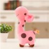 Une peluche de girafe rose à pois marrons, debout sur une table blanche.