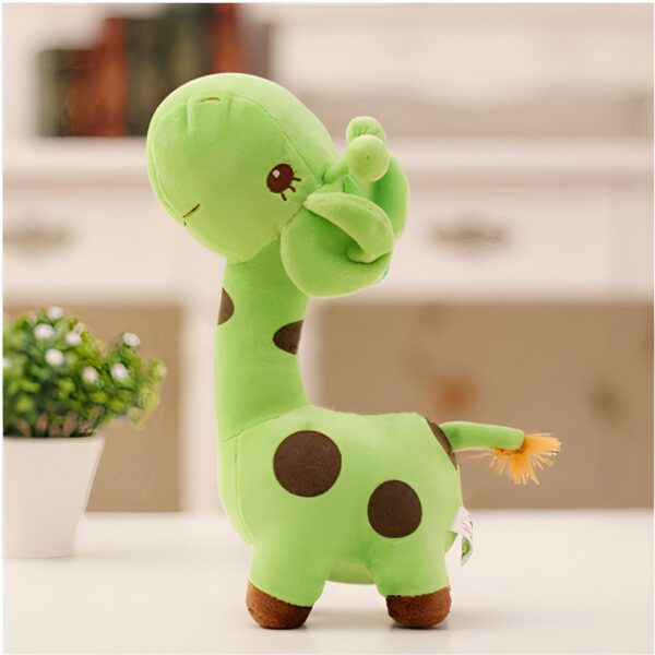 Une peluche de girafe verte avec des points bruns, debout sur une table blanche.