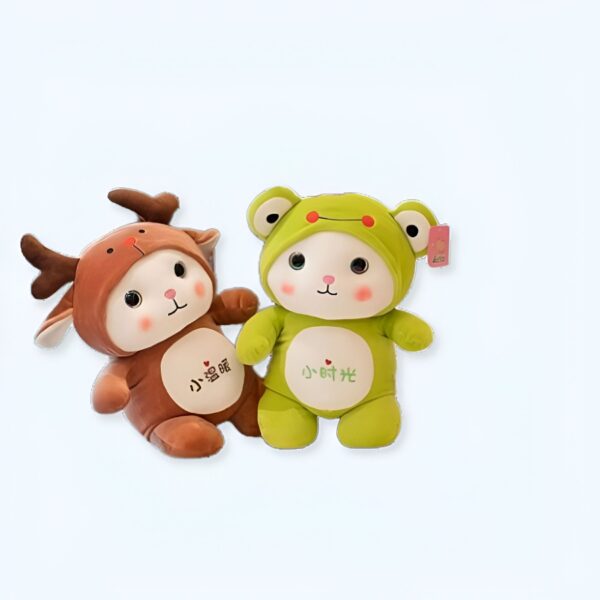 Deux peluches en forme d'animaux : un renne brun et une grenouille verte. Les peluches ont des visages souriants et des yeux noirs.