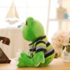 Une grenouille en peluche verte portant un t-shirt rayé bleu et vert assis sur une table en bois.