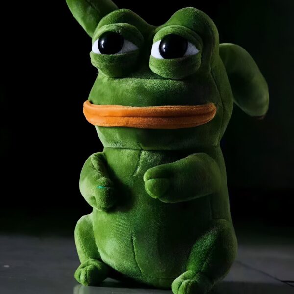 Une peluche verte en forme de grenouille avec une bouche orange et de grands yeux noirs.