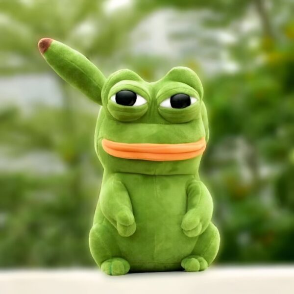 Peluche verte en forme de grenouille avec un grand sourire et des yeux noirs. La grenouille est assise sur un fond vert flou.
