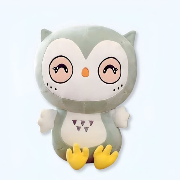 Une peluche verte et blanche en forme de hibou avec des yeux souriants et des pattes jaunes.