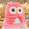 Peluche hibou rose avec un nœud sur la tête, assis sur une couverture rose.
