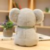Une peluche en forme de koala gris assise sur une table en bois.