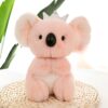 Une peluche rose en forme de koala portant une couronne. Elle est assise sur une surface en osier.