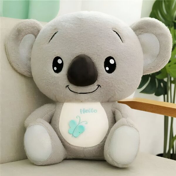 Peluche koala gris souriant avec un papillon bleu sur la poitrine, écrit "Hello" en dessous.