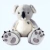 Grande peluche de koala gris et blanc assis sur un fond blanc. Le koala a de grands yeux noirs, un nez noir et une bouche souriante. Il est fait de fourrure douce et câline. Il est parfait pour les enfants de tous âges.