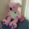 Gros ourson rose en peluche avec des pattes en forme de pattes d'ours et un petit ourson rose en peluche à côté.