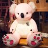 Grande peluche koala rose assis sur un banc en bois.