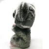 Peluche gris et blanc avec de grands yeux noirs assis sur un fond blanc.