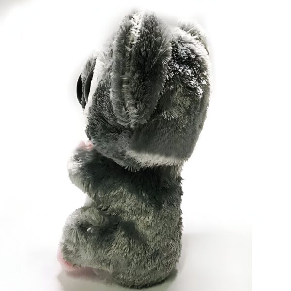 Peluche gris et blanc avec de grands yeux noirs assis sur un fond blanc.