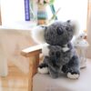 Une peluche de koala gris et blanc tenant un petit koala dans ses bras, assis sur un fauteuil en bois.
