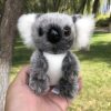 Une peluche de koala gris et blanc avec de grandes oreilles et un petit nez noir.