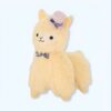 Peluche de lama beige portant un chapeau violet et un nœud papillon noir et blanc.