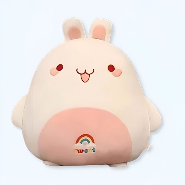 Une peluche blanche en forme de lapin avec des joues roses et un arc-en-ciel sur le ventre.