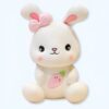 peluche-lapin-blanc-avec-noeud-et-carotte-jouet-peluche-adorable-1a Un lapin en peluche blanc avec un nœud rose et une carotte brodée sur le ventre.