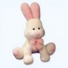 Un lapin en peluche blanc avec des oreilles roses et un nœud rose.