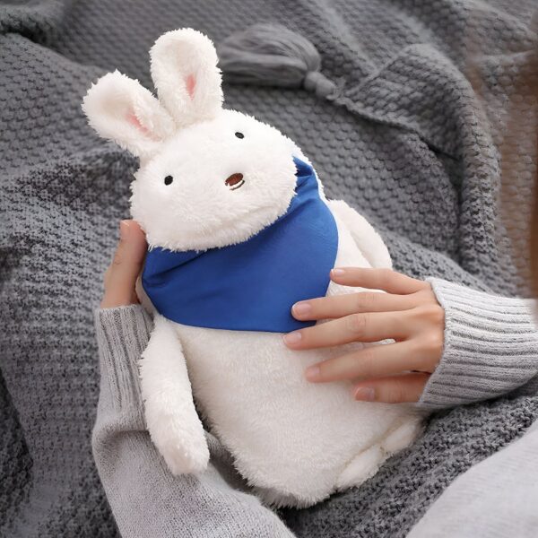 peluche-lapin-bouillotte-chauffante-brun-avec-noeud-rouge-3a-2 Une peluche blanche en forme de lapin portant un bandana bleu, tenue par une personne dans un pull gris.