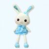 Une peluche de lapin blanc portant une robe bleue et des chaussures bleues avec le mot "Love" écrit sur son oreille.
