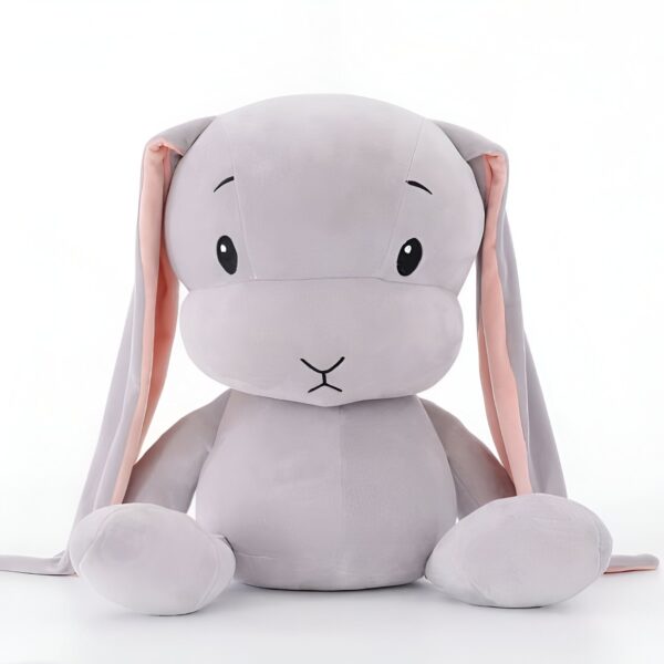 Gros lapin en peluche gris avec de longues oreilles roses assis sur un fond blanc.