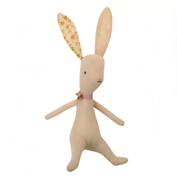 Un lapin en peluche beige avec des oreilles à motifs dorés et un nœud rose autour du cou.