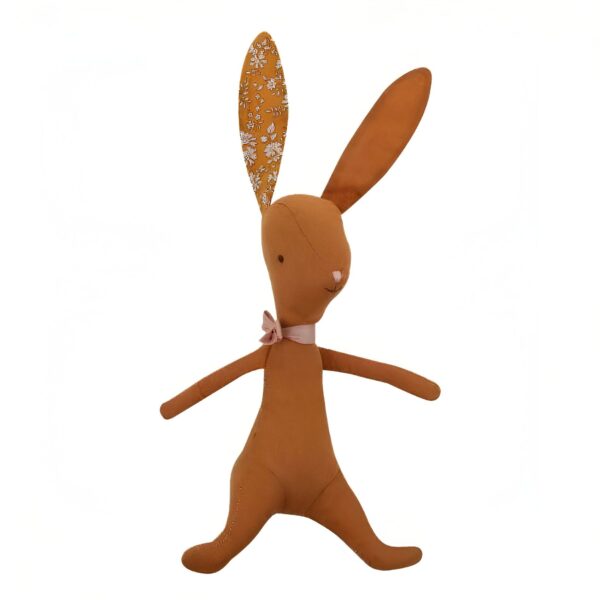 Un lapin en peluche marron avec un nœud rose et des oreilles en tissu à fleurs.
