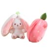 Un lapin en peluche blanc avec de grandes oreilles roses et une fraise en peluche rose.