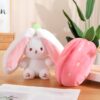 Une peluche de lapin blanc avec de grandes oreilles roses et une peluche en forme de fraise rose.