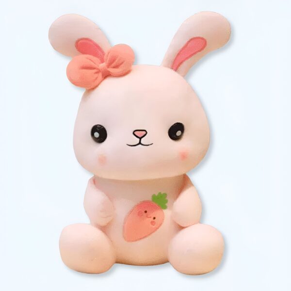 Un lapin rose en peluche avec un nœud rose et une carotte sur le ventre.