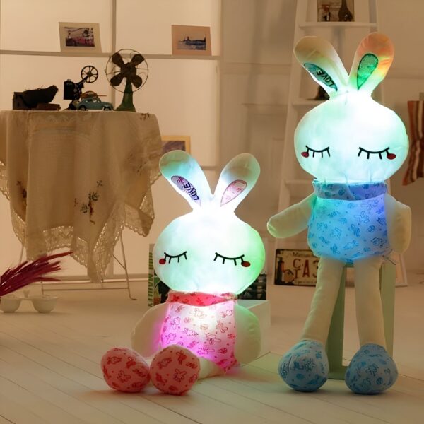 Deux lapins en peluche lumineux, l'un rose et l'autre bleu, avec des yeux fermés. Ils sont assis sur le sol.