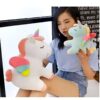 Une jeune femme tenant deux peluches de licornes, l'une blanche et l'autre bleue, avec des ailes arc-en-ciel.