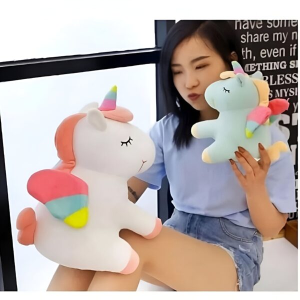 Une jeune femme tenant deux peluches de licornes, l'une blanche et l'autre bleue, avec des ailes arc-en-ciel.