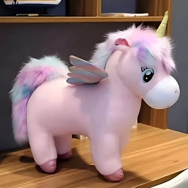 Une licorne rose en peluche avec des ailes dorées et une crinière et une queue arc-en-ciel.