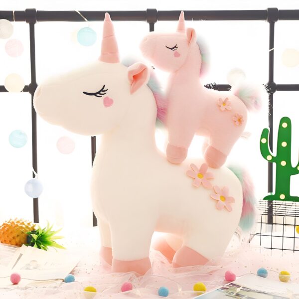 peluche-licorne-magique-douce-cadeau-enfant-5a-2 Deux licornes en peluche, une grande blanche avec une petite rose sur le dos, toutes les deux avec des fleurs brodées sur leur corps.
