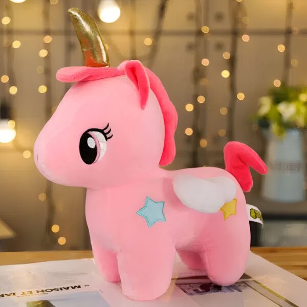 Une peluche rose en forme de licorne avec une corne dorée, des ailes blanches et des étoiles bleues.
