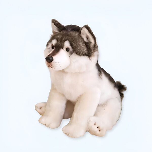 Un adorable chiot en peluche gris et blanc, assis et regardant vers la droite.