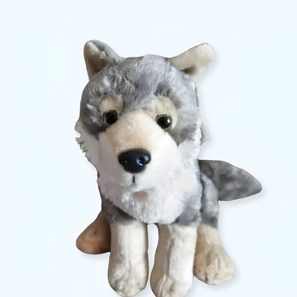 Peluche de loup gris assis sur un fond blanc.
