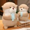 Deux peluches en forme de loutre tenant un poisson bleu. La grande loutre est debout sur un sol en bois et la petite loutre est sur un panier métallique blanc.