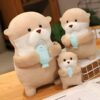 Trois peluches de loutre tenant un poisson bleu. La plus grande loutre est en position debout, les deux autres sont assises.