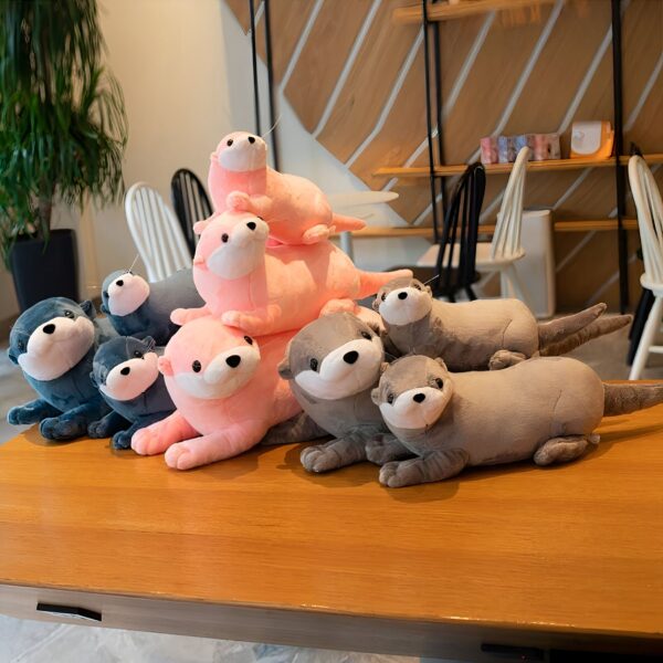 peluche-loutre-lola-jouet-en-peluche-doux-et-calin-pour-enfants-4a Jouets en peluche de loutre dans différentes couleurs, posés sur une table en bois.