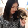 Une jeune femme souriante tenant une peluche de loutre.