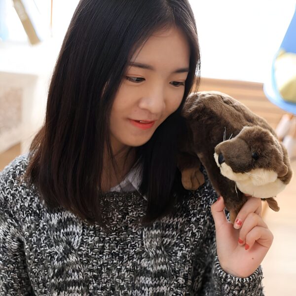 Une jeune femme souriante tenant une peluche de loutre.